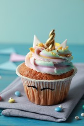 Cute sweet unicorn cupcake on light blue wooden table, closeup