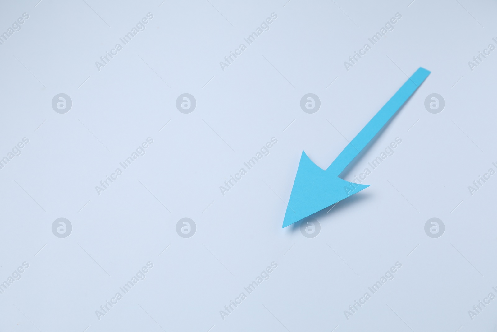 Photo of Light blue paper arrow on white background, space for text