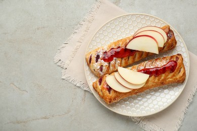 Fresh tasty puff pastry with jam and apples on white textured table, top view. Space for text