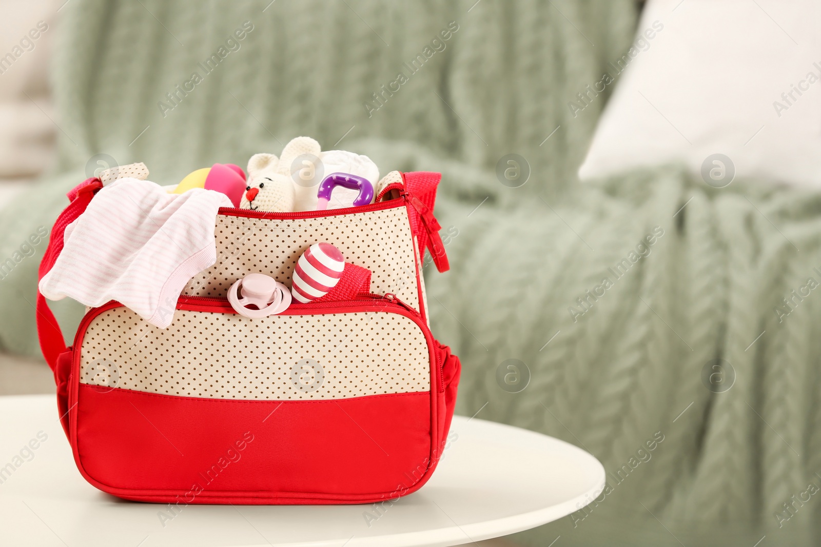 Photo of Mother's bag with baby's stuff on white table indoors. Space for text