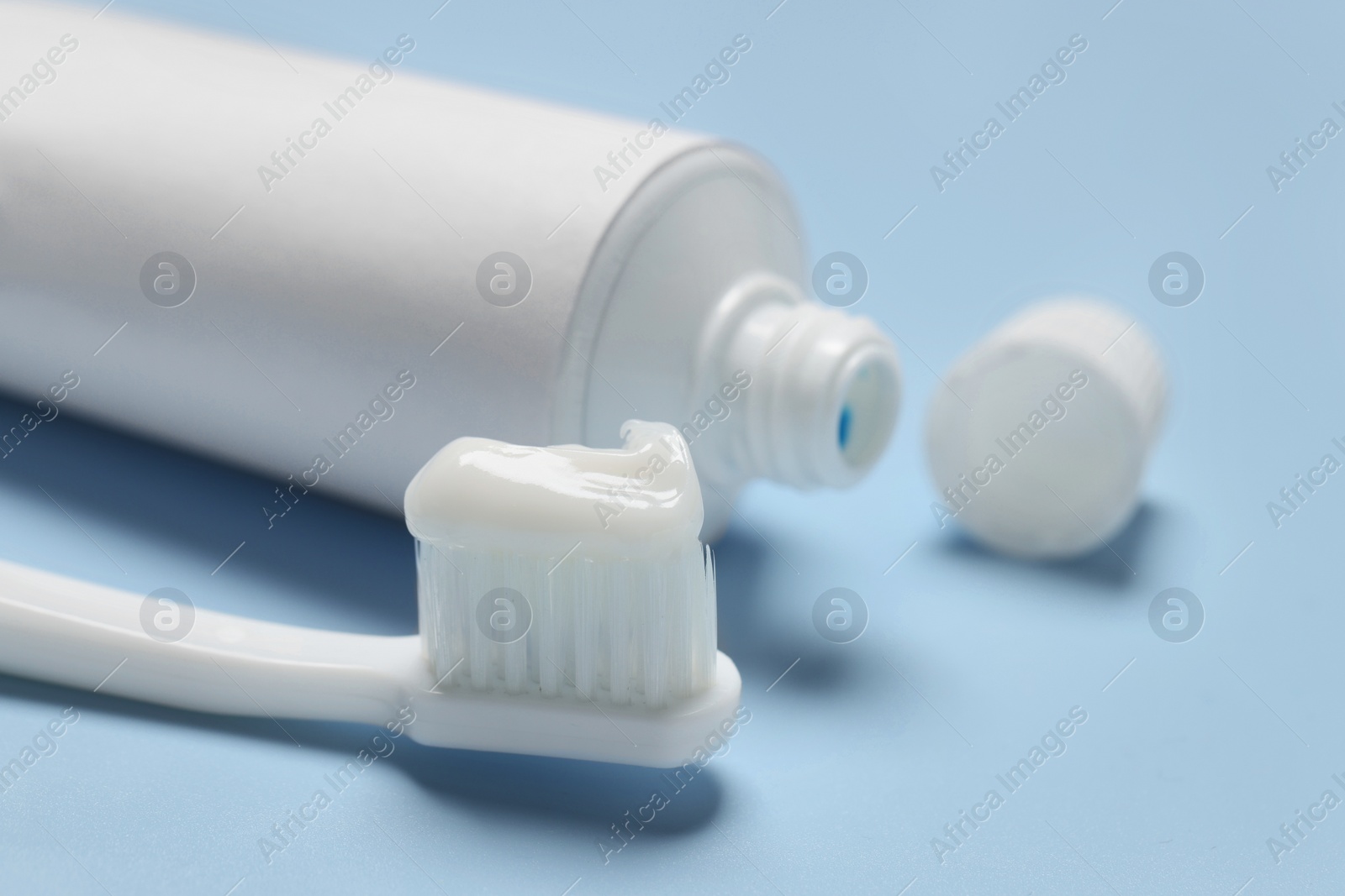 Photo of Plastic toothbrush with paste and tube on light background, closeup