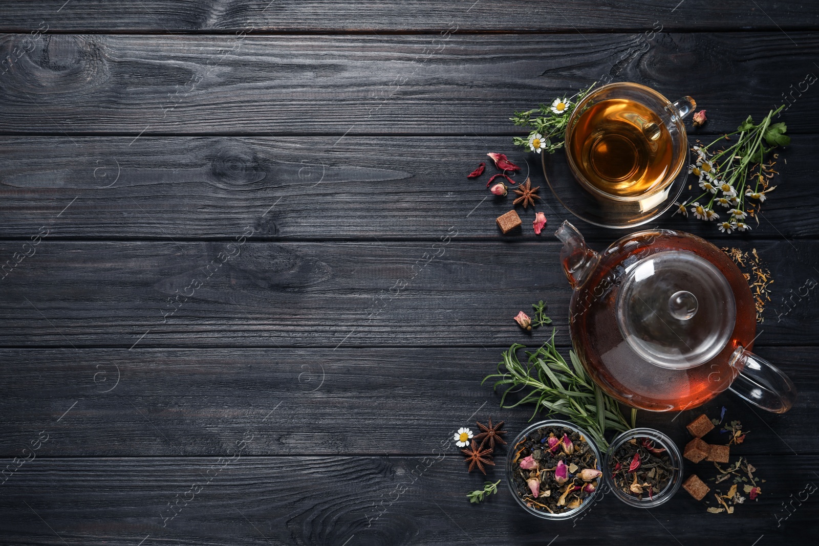 Photo of Flat lay composition with freshly brewed tea and dry leaves on black wooden table. Space for text