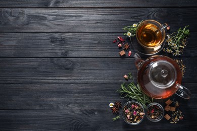 Photo of Flat lay composition with freshly brewed tea and dry leaves on black wooden table. Space for text