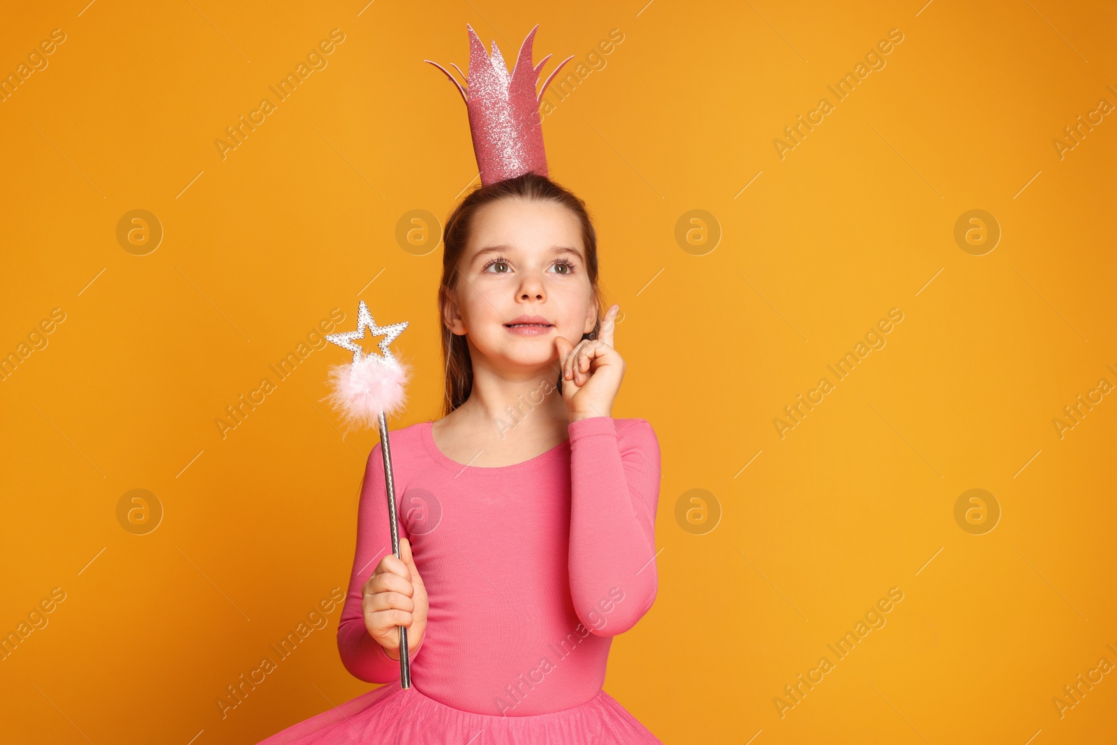 Photo of Cute girl in pink crown with magic wand on yellow background, space for text. Little princess