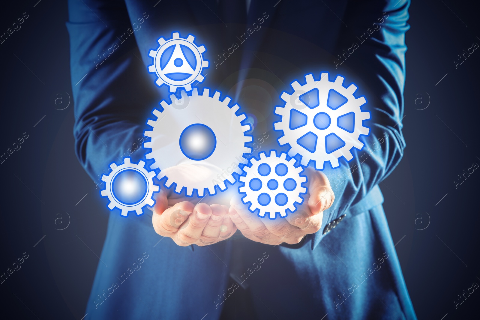 Image of Businessman demonstrating gear mechanism on dark background, closeup