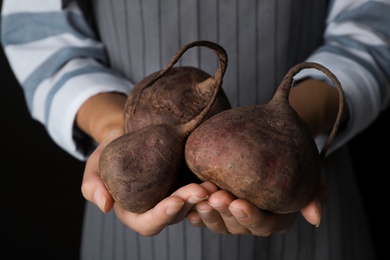 Photo of Woman holding ripe beets on black background