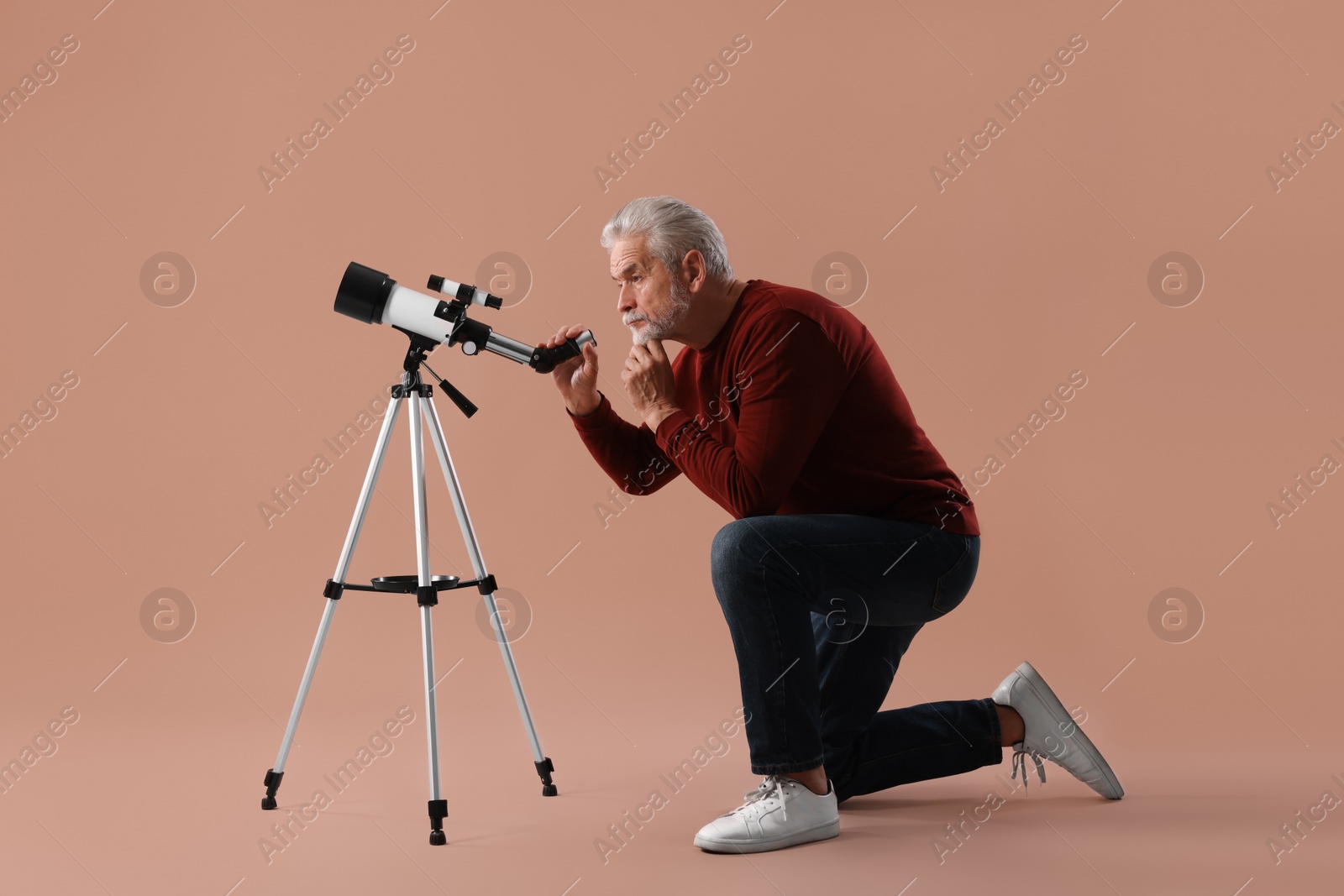 Photo of Senior astronomer with telescope on brown background