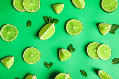 Photo of Flat lay composition with fresh juicy limes on green background