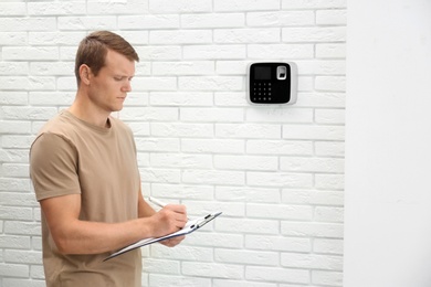 Male technician checking security alarm system indoors
