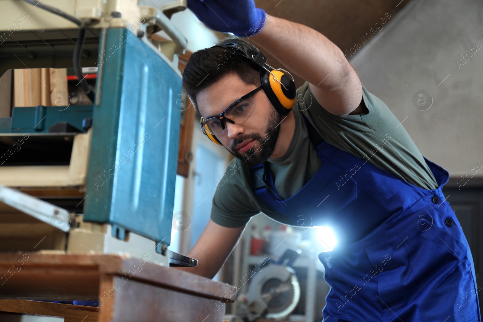 Photo of Professional carpenter working with grinding machine in shop