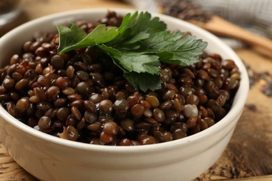 Photo of Delicious lentils with parsley in bowl on table, closeup