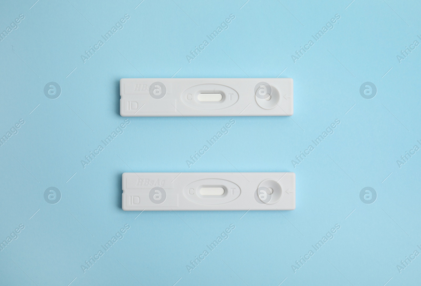 Photo of Two disposable express tests for hepatitis on light blue background, flat lay