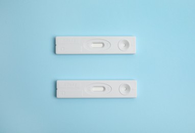 Photo of Two disposable express tests for hepatitis on light blue background, flat lay