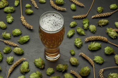 Photo of Glass of beer, fresh green hops and spikes on dark grey table