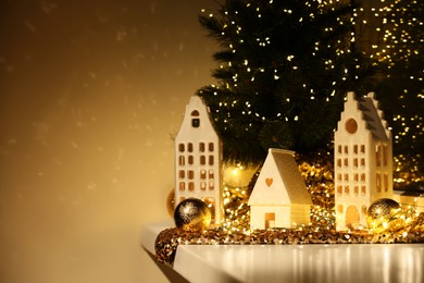 Photo of Beautiful decorative houses and small Christmas tree on window sill indoors. Space for text