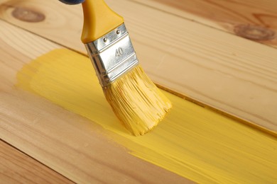 Photo of Applying yellow paint onto wooden surface, closeup. Space for text