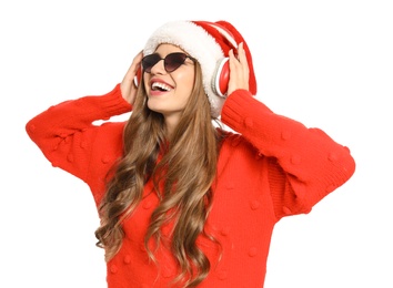 Happy young woman listening to Christmas music on white background
