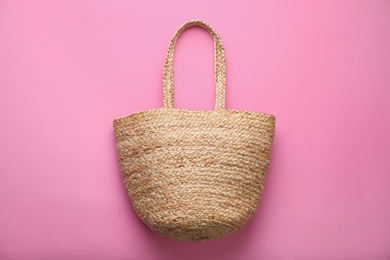 Photo of Elegant woman's straw bag on pink background, top view