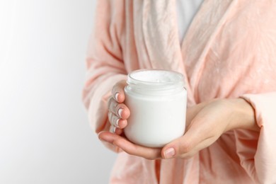 Woman holding jar of hand cream on white background, closeup. Space for text