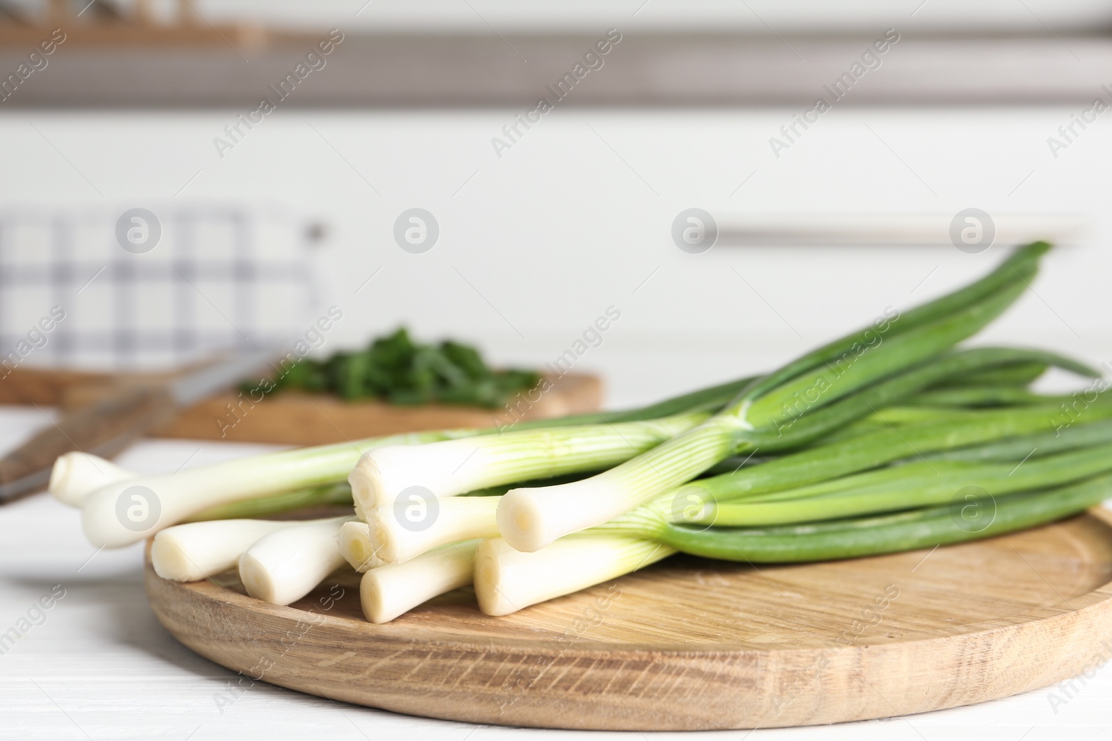 Photo of Fresh green spring onions on wooden board, closeup