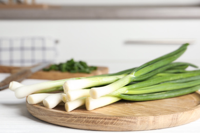 Fresh green spring onions on wooden board, closeup