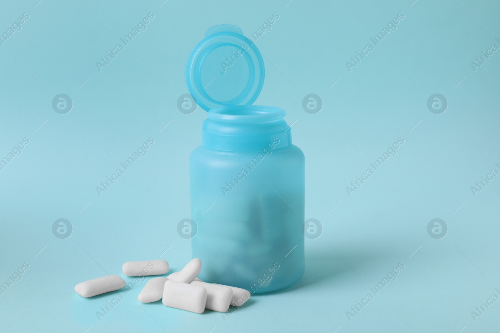 Photo of Color jar with chewing gums on light blue background