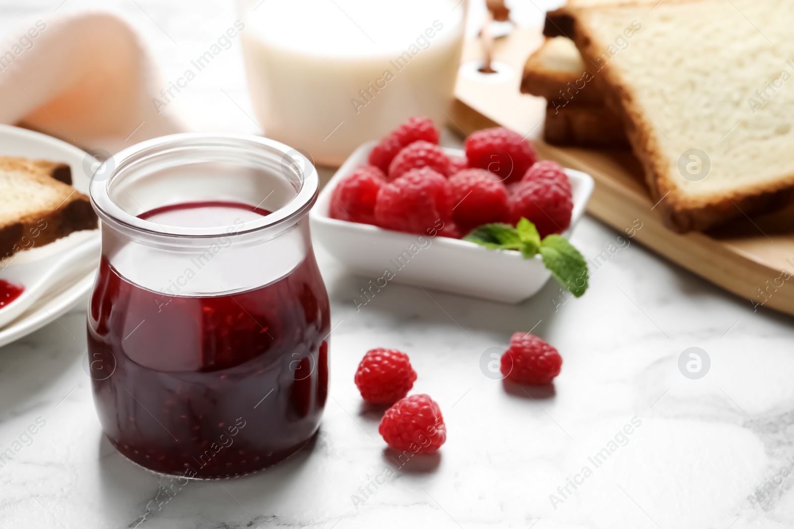 Image of Sweet raspberry jam and toasts for breakfast on white marble table