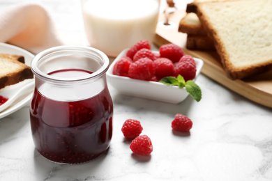 Sweet raspberry jam and toasts for breakfast on white marble table