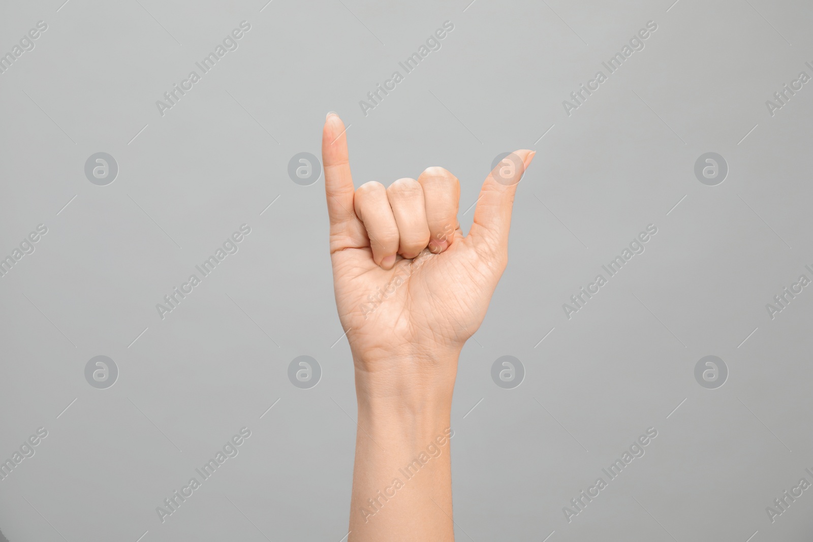 Photo of Woman showing Y letter on grey background, closeup. Sign language