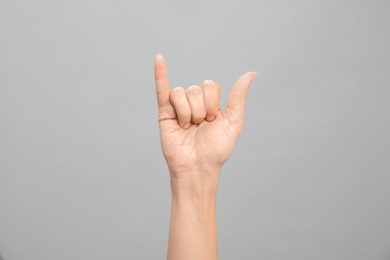 Photo of Woman showing Y letter on grey background, closeup. Sign language