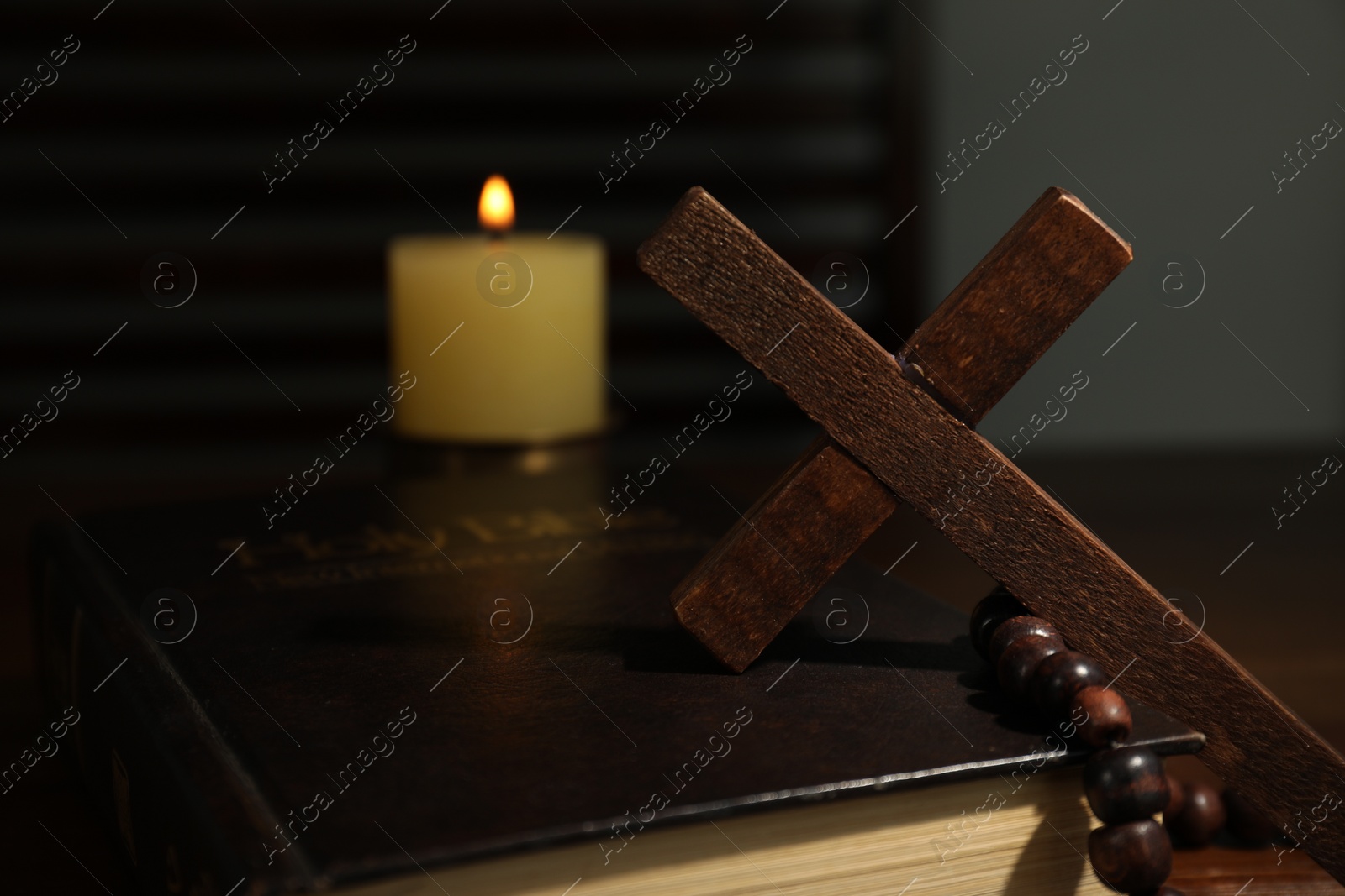 Photo of Cross, rosary beads, Bible and church candle on table, closeup
