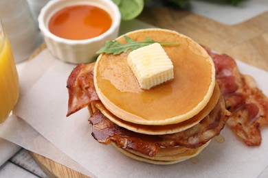 Photo of Delicious pancakes with bacon, butter, arugula and honey on table, closeup