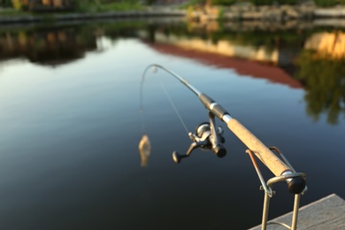 Photo of Fishing rod with caught fish at lake on sunny day