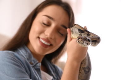 Photo of Young woman with her boa constrictor at home, focus on hand