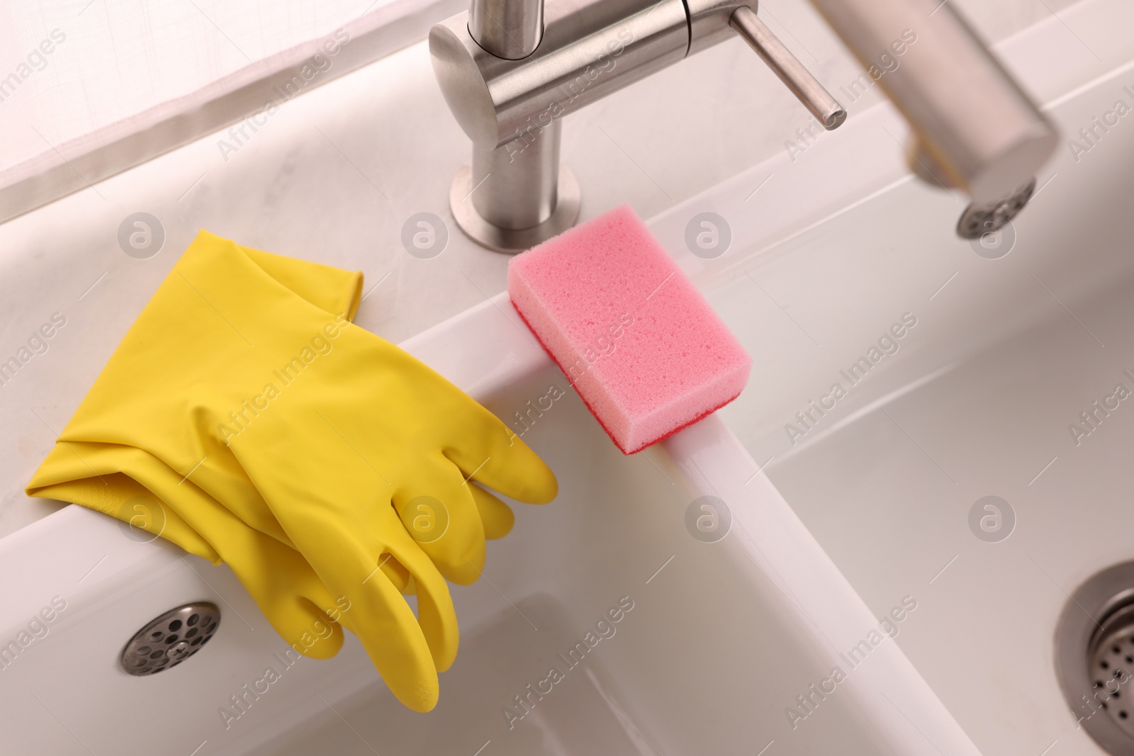 Photo of Sponge and rubber gloves on kitchen sink indoors, above view