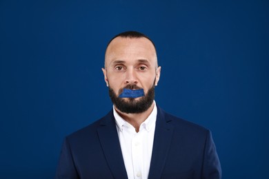 Image of Mature man with taped mouth on blue background. Speech censorship