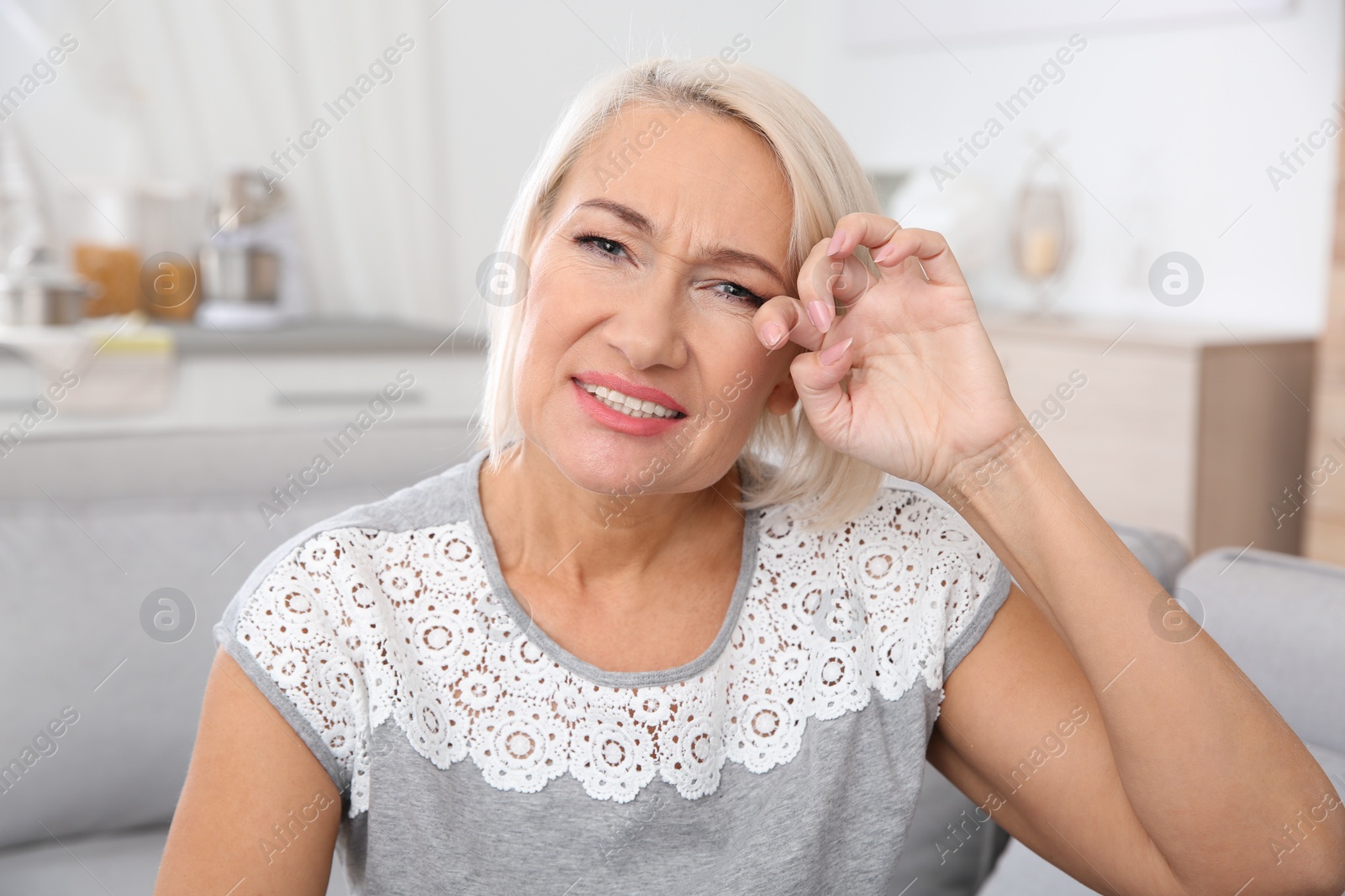 Photo of Mature woman rubbing eye at home. Annoying itch