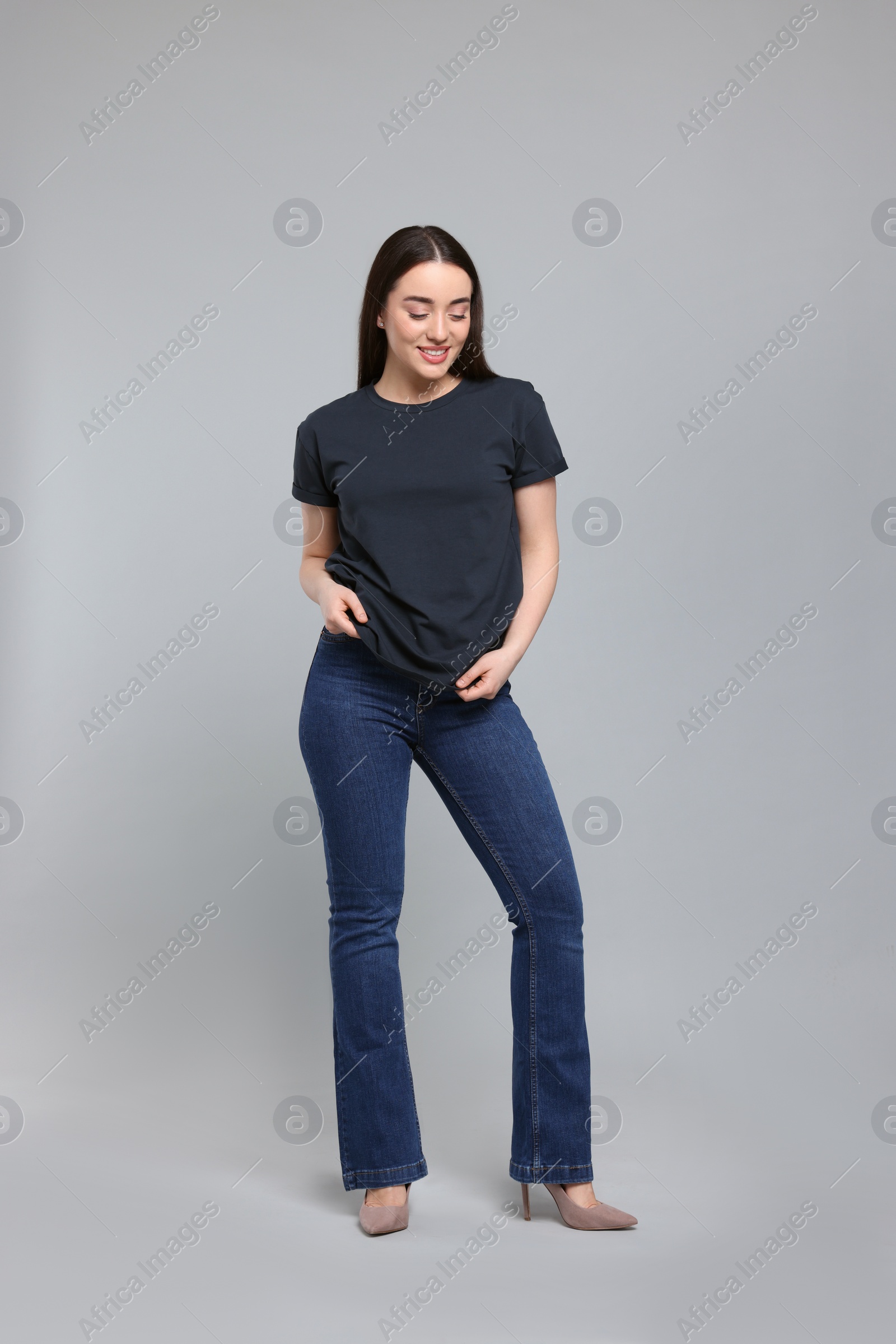 Photo of Young woman in stylish jeans on grey background