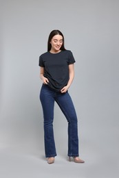 Photo of Young woman in stylish jeans on grey background