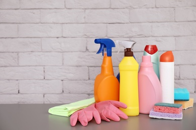 Set of cleaning supplies on table near brick wall