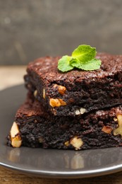 Photo of Delicious brownies with nuts and mint on grey plate, closeup