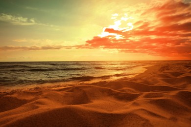 Picturesque view of beautiful orange sky with clouds over beach and sea at sunset