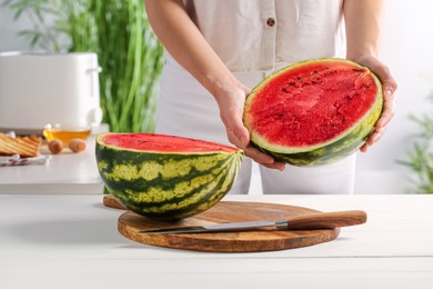 Woman with delicious cut watermelon at white wooden table in kitchen, closeup
