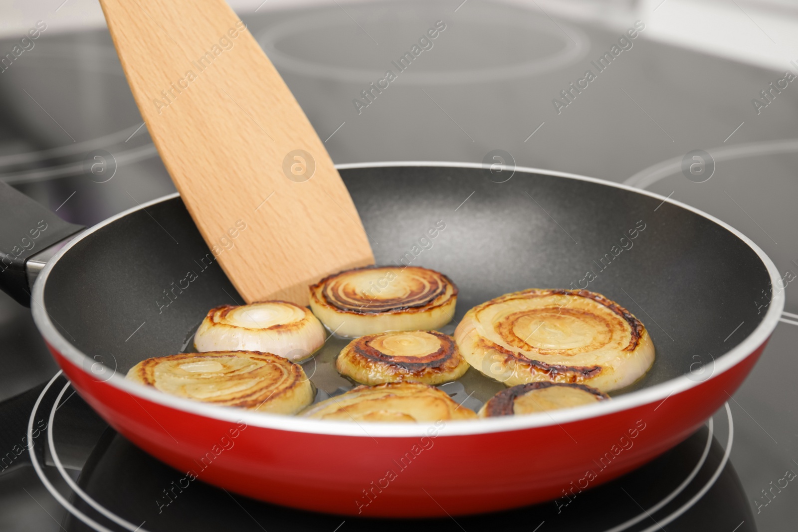 Photo of Cooking onion rings in frying pan on stove, closeup