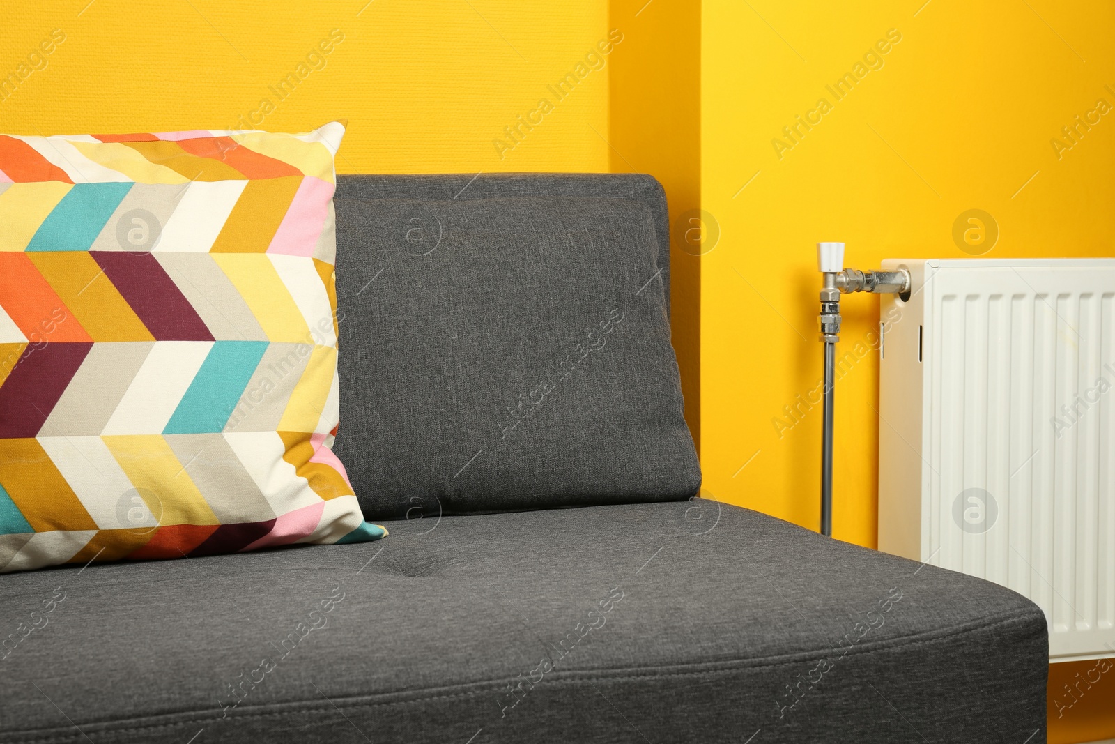 Photo of Bright cushion on grey sofa in room