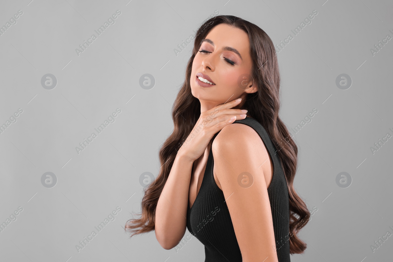 Photo of Hair styling. Beautiful woman with wavy long hair on grey background