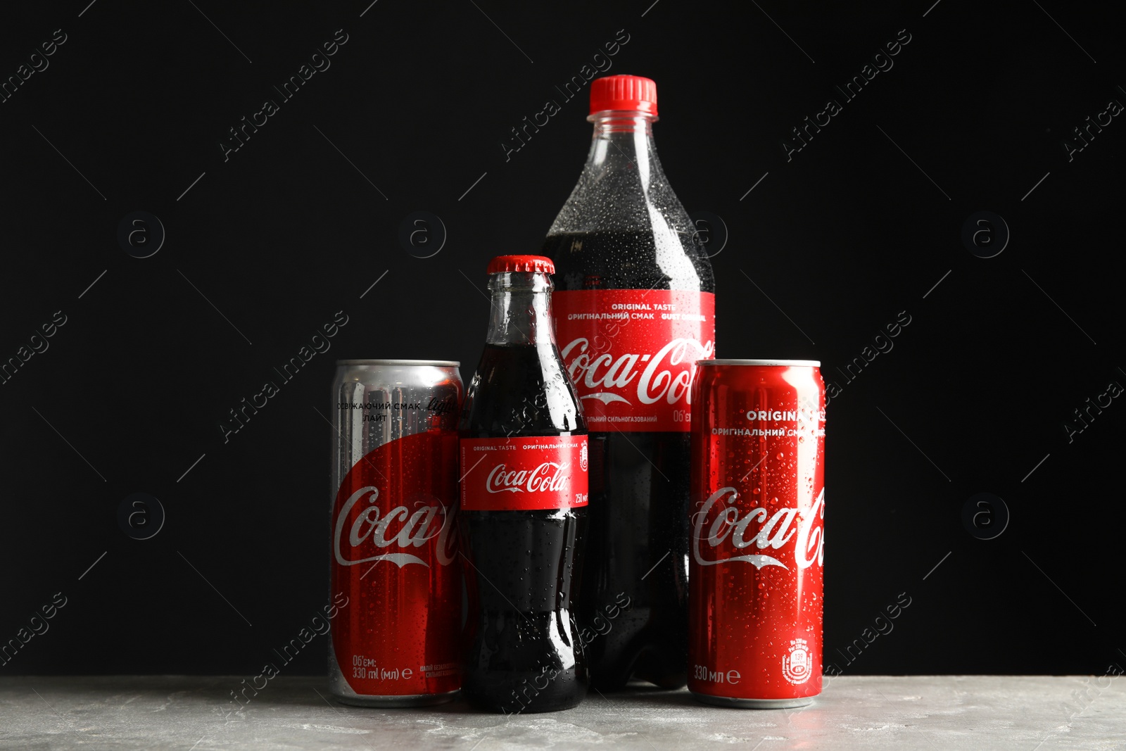 Photo of MYKOLAIV, UKRAINE - NOVEMBER 15, 2018: Bottles and cans with Coca Cola on table against black background