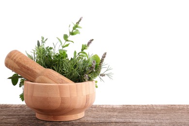 Photo of Mortar, pestle and different herbs on wooden table against white background. Space for text