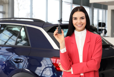 Photo of Saleswoman with key near car in dealership