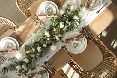 Photo of Elegant table setting with beautiful floral decor and burning candles, top view